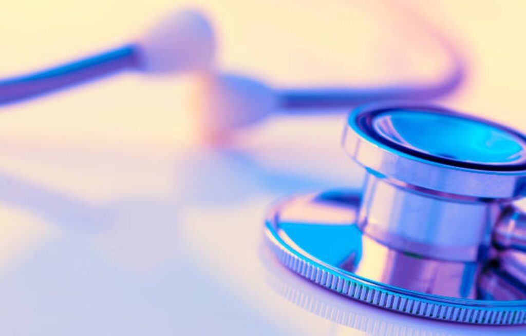 Close-up of a stethoscope with a reflective surface, showing metal chest piece and flexible tubing in a warm and cool color gradient.